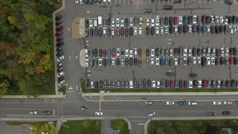 Vertical-overhead-drone-shot-of-busy-parking-lot-with-cars-driving-within-it