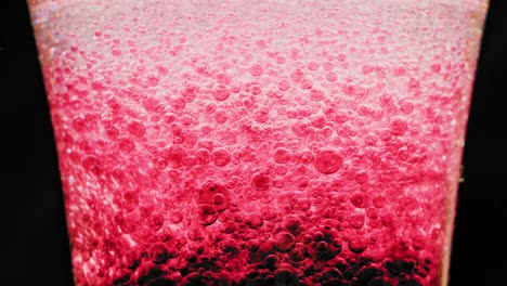 Makroaufnahme-Von-Funkelnden-Roten-Blasen,-Die-In-Einem-Glas-Mit-Hellem-Hintergrund-Herumschweben