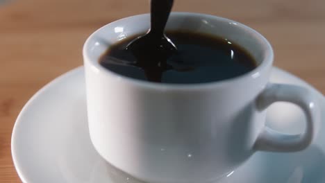 Close-Interior-Shot-of-Stirring-Black-Coffee-With-Metal-Spoon-at-Night