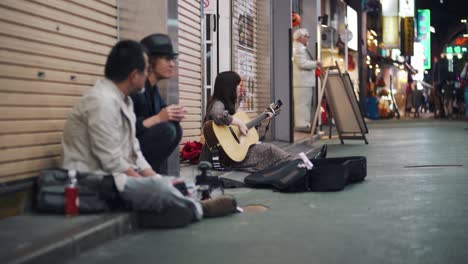 Japanese-Female-Singer-Songwriter-Busking-In-The-Street---Female-Guitarist-Singing-In-the-Street-Of-Tokyo,-Japan-At-Night