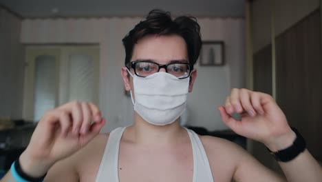 a-young-guy-with-glasses-puts-a-mask-on-his-face,-then-takes-it-off
