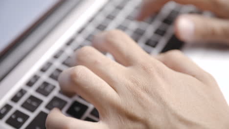 Close-up-from-above-of-young-male-hands-typing-on-laptop-keyboard