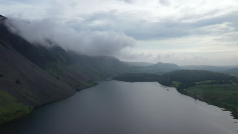 Aerial-wide-shot-of-a-lake-next-to-a-mountain,-in-the-English-countryside