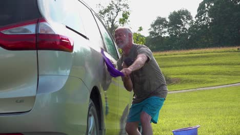 Slow-motion-of-dancing-crazy-man-doing-the-twist-while-washing-his-car-with-hose-and-soapy-sponges