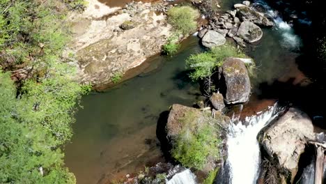 Drone-footage-moving-backward-with-the-flow-of-the-stream-to-a-water-fall-at-Coquille-falls