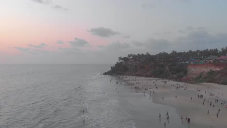 Forward-moving-aerial-showing-tourists-enjoying-their-holiday-on-Varkala-beach-during-sunset