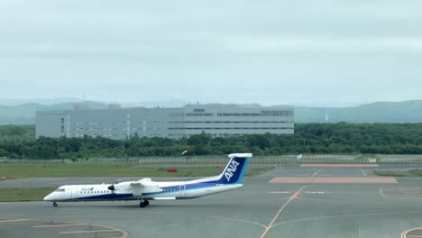 Profile-view-of-large-white-airplane-on-asphalt-tarmac-leaving-and-taking-off-at-Chitose-airport,-Japan,-static