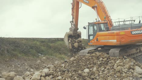 Digger-picking-up-and-moving-stone-with-old-worn-bucket-attachment
