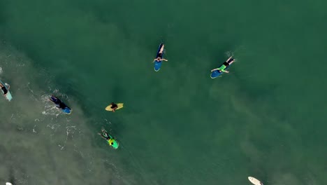 Rotating-vertical-aerial-footage-showing-surfers,on-their-surf-boards,enjoying-the-recreational-sports-of-surfing-on-water
