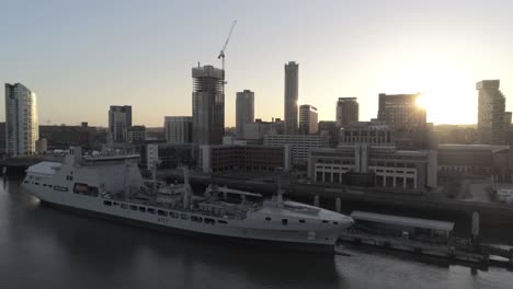 RFA-Navy-Tiderace-military-tanker-on-Liverpool-cityscape-waterfront-at-sunrise-aerial-orbit-low-left-view