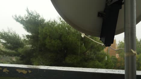 Alte-Satellitenschüssel,-Die-An-Einem-Stürmischen-Tag-Mit-Starkem-Regen-Und-Wind-Mit-Einer-Kiefer-Im-Hintergrund-In-Der-Nähe-Von-Marseille-In-Südfrankreich-Auf-Einem-Balkon-Mit-Einem-Stück-Weißem-Klebeband-Gehalten-Wird
