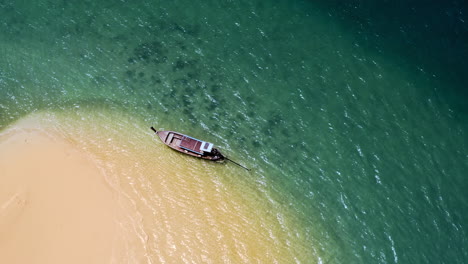 Single-longtail-boat-floating-at-lonely-island-in-thailand,-top-view,-Drone