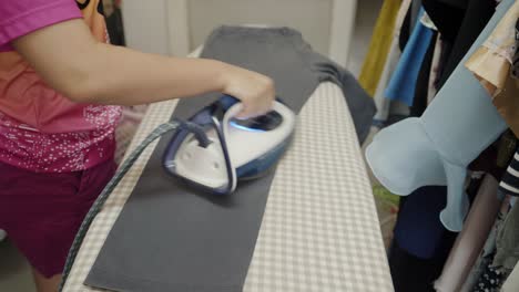 Closeup-of-a-woman-ironing-clothing-by-stream-iron-on-board-at-home