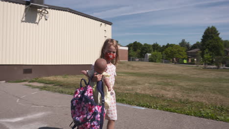 A-little-girl-walking-through-a-school-yard-wearing-a-face-mask