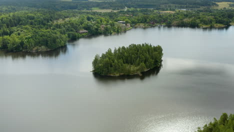 Aerial,-tilt-up,-drone-shot-over-a-island-on-lake-Bruntrasket,-revealing-the-Fagervik-manor,-the-church-and-the-old-steelwork-village,-in-Inkoo,-Uusimaa,-Finland