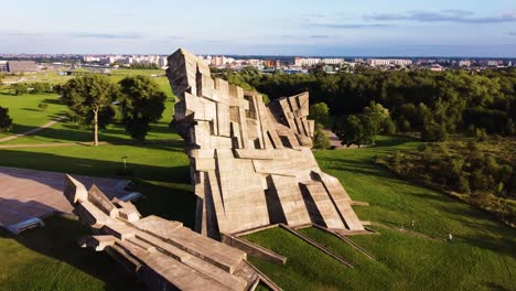 Memorial-of-the-Victims-of-Nazism-at-the-Ninth-Fort-of-Kaunas-city,-Lithuania-in-flying-around-drone-aerial-shot-with-Kaunas-city-in-the-distance