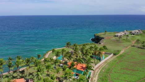 Villas-on-the-edge-of-a-cliff-in-the-Caribbean,-coconut-trees-and-turquoise-blue-water-characterize-the-southern-part-of-the-Dominican-Republic