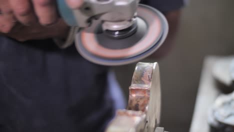 Craftsman-polishes-a-violins-body-using-a-mechanical-hand-grinder-in-a-workshop