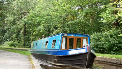 Historic-British-staycation-canal-boats-tourism-steering-through-calming-Welsh-woodland-greenery