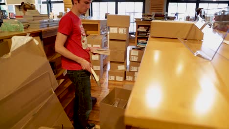 Man-unboxes-books-to-put-on-wooden-shelves
