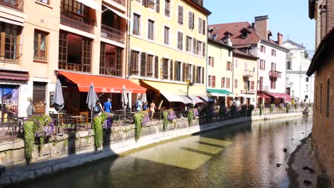Tilt-up-shot-of-Tourists-with-protective-masks-walking-next-to-a-water-channel-in-Annecy,-France,-during-Coronavirus-pandemia