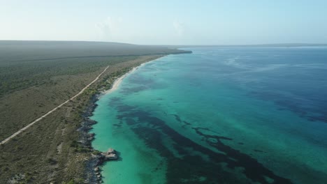 Impressive-aerial-shot-with-drone-of-the-coasts-of-Cabo-Rojo,-Pedernales,-on-a-clear-morning-overlooking-the-turquoise-blue-water-and-the-vegetation-of-the-area