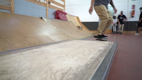 Low-angle-shot-of-male-skateboarder-jumping-on-small-wooden-ramp-and-sliding-over