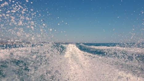 Low-angle-pov-of-motor-boat-wake-trail-and-water-spray-on-sea-surface