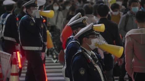 Group-Of-Cops-Using-Yellow-Megaphones-While-Controlling-The-Crowd-At-Shibuya-Crossing-On-Halloween-Night-2020---Medium-Shot