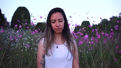 young-latin-woman-sad-and-thinking-deeply-in-the-middle-of-a-beautiful-purple-field-with-tinny-flowers