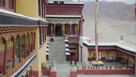 Two-tibetan-buddhist-monks-walk-through-the-courtyard-of-a-tibetan-monastery-in-Ladakh,-India