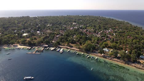 Rückwärtige-Luftaufnahmen-Der-Wunderschönen-Insel-Gili-Air-Mit-Bäumen,-Meeresufer,-Booten-Und-Hotels-An-Sonnigen-Tagen