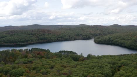 Picturesque-lake-in-a-vast-forest---aerial-pull-back-view-in-autumn