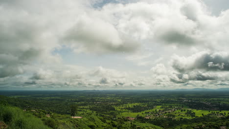Fluffy-clouds-rolling-over-lush-green-rice-paddies-during-rainy-season-on-the-planes-of-Cambodia,-South-East-Asia