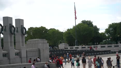 Pilares-Y-Bandera-Estadounidense-En-El-Memorial-De-La-Segunda-Guerra-Mundial-En-Washington-Dc-Con-Gente-Caminando-Durante-El-Día---ángulo-Alto,-Plano-General