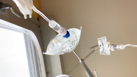 Two-intravenous-drips-hang-from-their-stand,-administering-medication