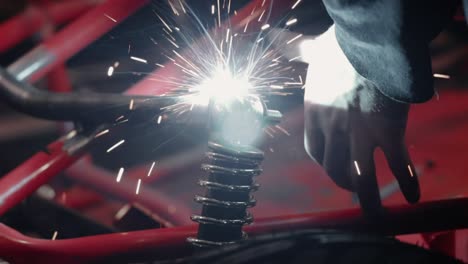 Bright-sparks-eject-from-welding-metal-together-in-workshop,-close-up