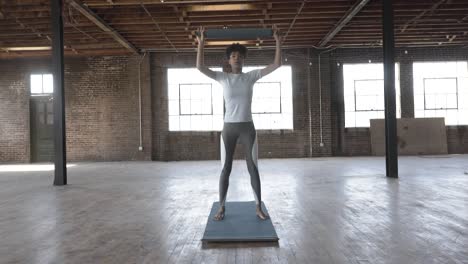 Black-woman-performing-overhead-presses-on-yoga-mat