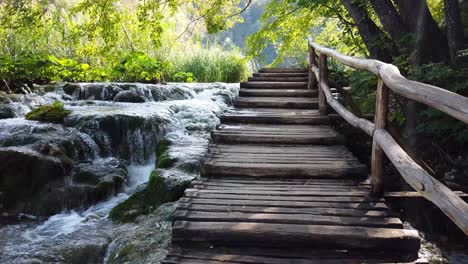 Moving-up-some-wooden-stairs-along-a-series-of-waterfalls-at-Plitvice-Lakes-National-Park-in-Croatia,-Europe