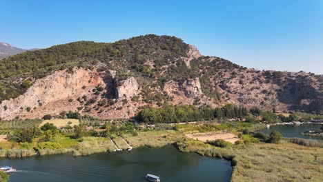 Drone-shooting-of-a-mountain-temple-and-the-vicinity-of-the-city-of-Dalyan-flying-over-the-fields-and-the-mountain-river