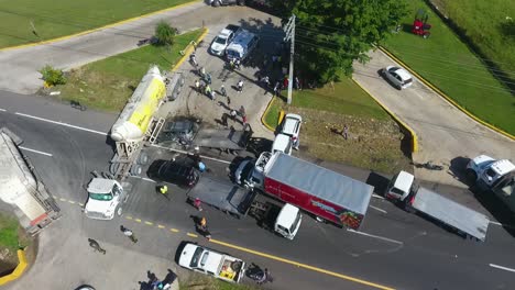 Drone-shot-of-a-collision-accident,-a-car-under-a-oil-truck-and-a-lorry-wrecked-to-pieces,-in-Mexico,-Central-America---descending,-Aerial-view