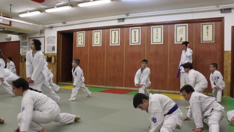 Estudiantes-En-Clase-De-Karate-Estirándose-Para-Calentar