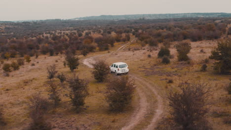 Jeep-Blanco-Conduciendo-Por-Un-Camino-Rural-De-Tierra-En-Una-Estepa-Marrón-De-Otoño