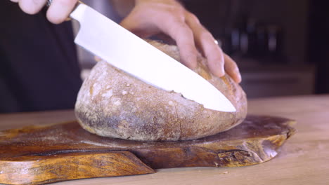 Man-Slicing-Fresh-Home-Baked-Sourdough-Bread-In-The-Kitchen---close-up,-slider-left-shot