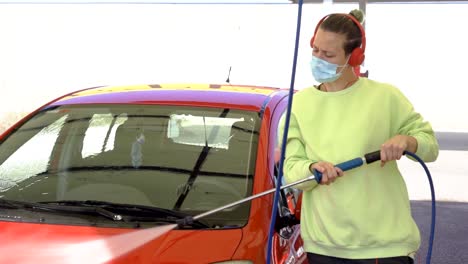 Woman-cleaning-car-with-mask-while-listening-to-music,-new-normal