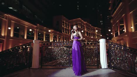 Girl-Singing-At-The-Bridge-With-Love-Padlocks-At-The-Venice-Grand-Canal-In-Mckinley-Hill,-Taguig,-Philippines---Virtual-Venetian-Concerto---A-Tribute-To-Frontliners-In-COVID-19-Pandemic