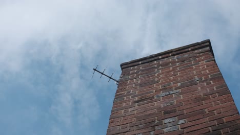 Light-clouds-passing-behind-brick-chimney-with-TV-antennae