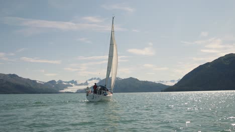 Cruising-Sailboat-On-A-Calm-Sea-Amidst-A-Beautiful-Mountain-View-Of-Alaska-USA--panning-aerial-shot