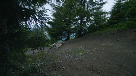 Mountain-biker-cuts-a-corner-and-does-a-jump-in-a-dark-forest