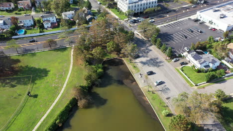 An-aerial-shot-over-a-green-pond-in-a-suburban-neighborhood-on-Long-Island,-NY